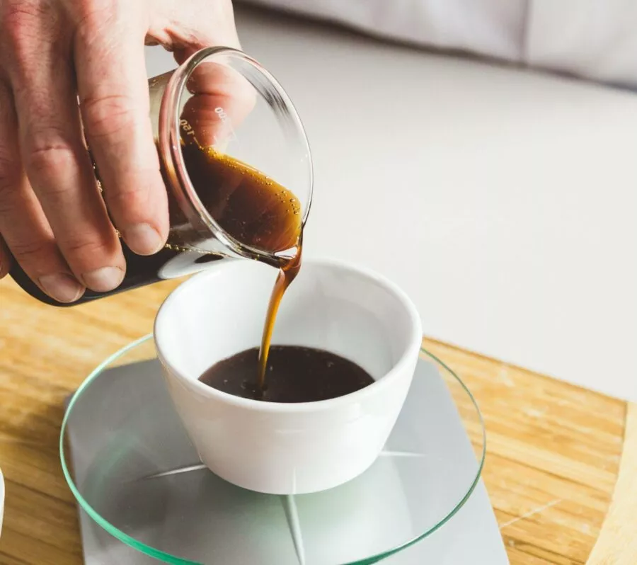 Beaker of beef bone broth pouring into a ramekin on scales