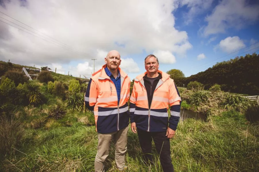 Team member with environmental manager in lush Taranaki riparian planting area