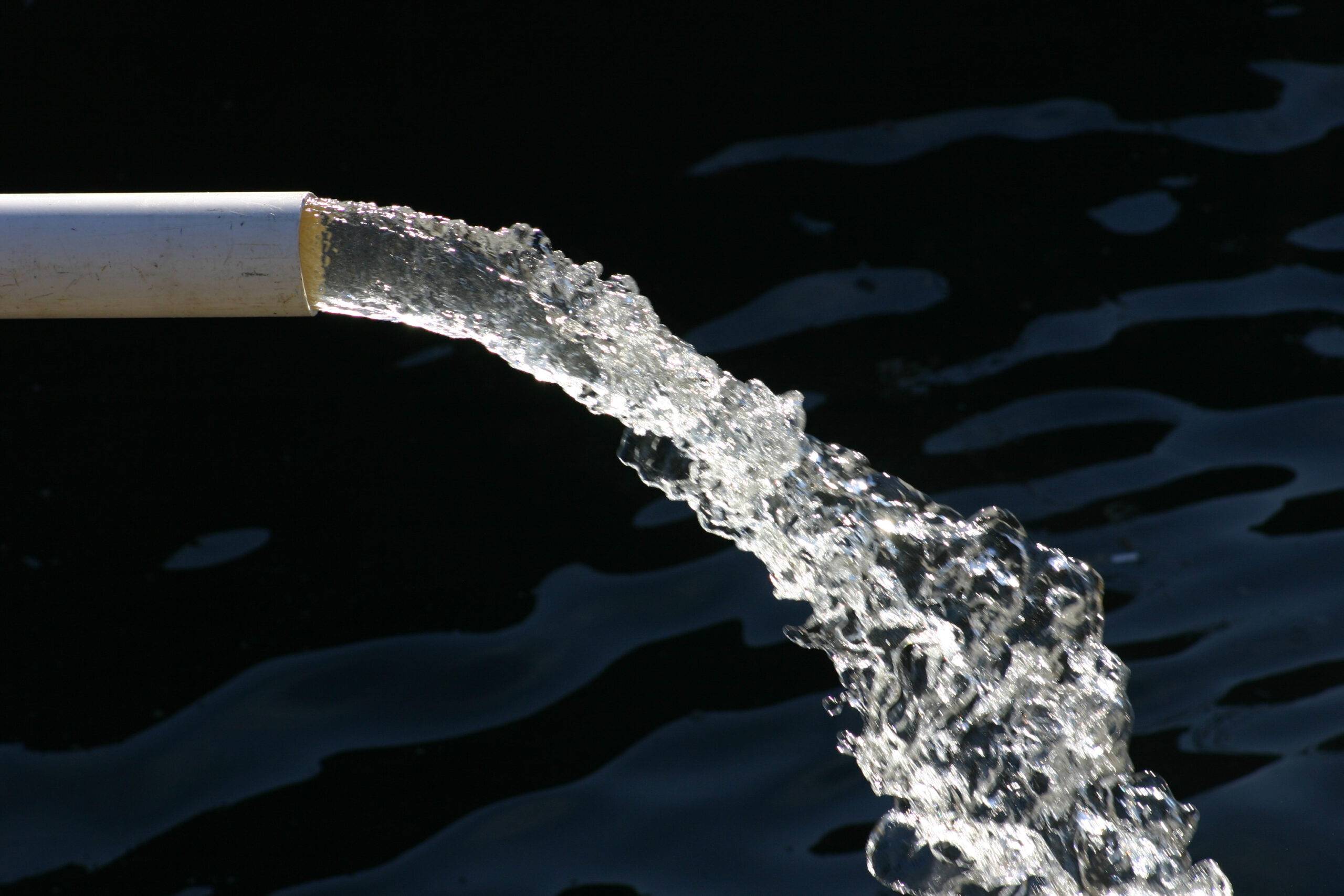 A pipe with fresh clear water flowing from it.